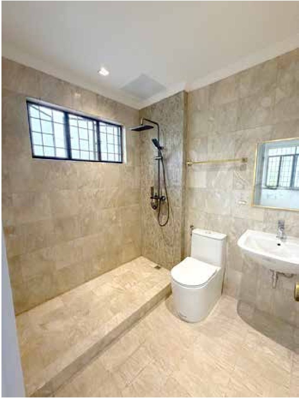 New bathroom in travertine-toned tile with walk-in rain shower