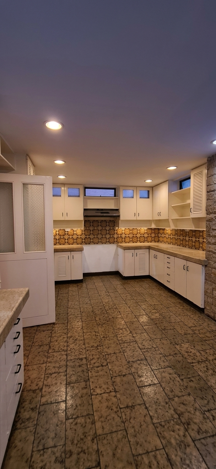 Galley kitchen with full white cabinetry and patterned backsplash