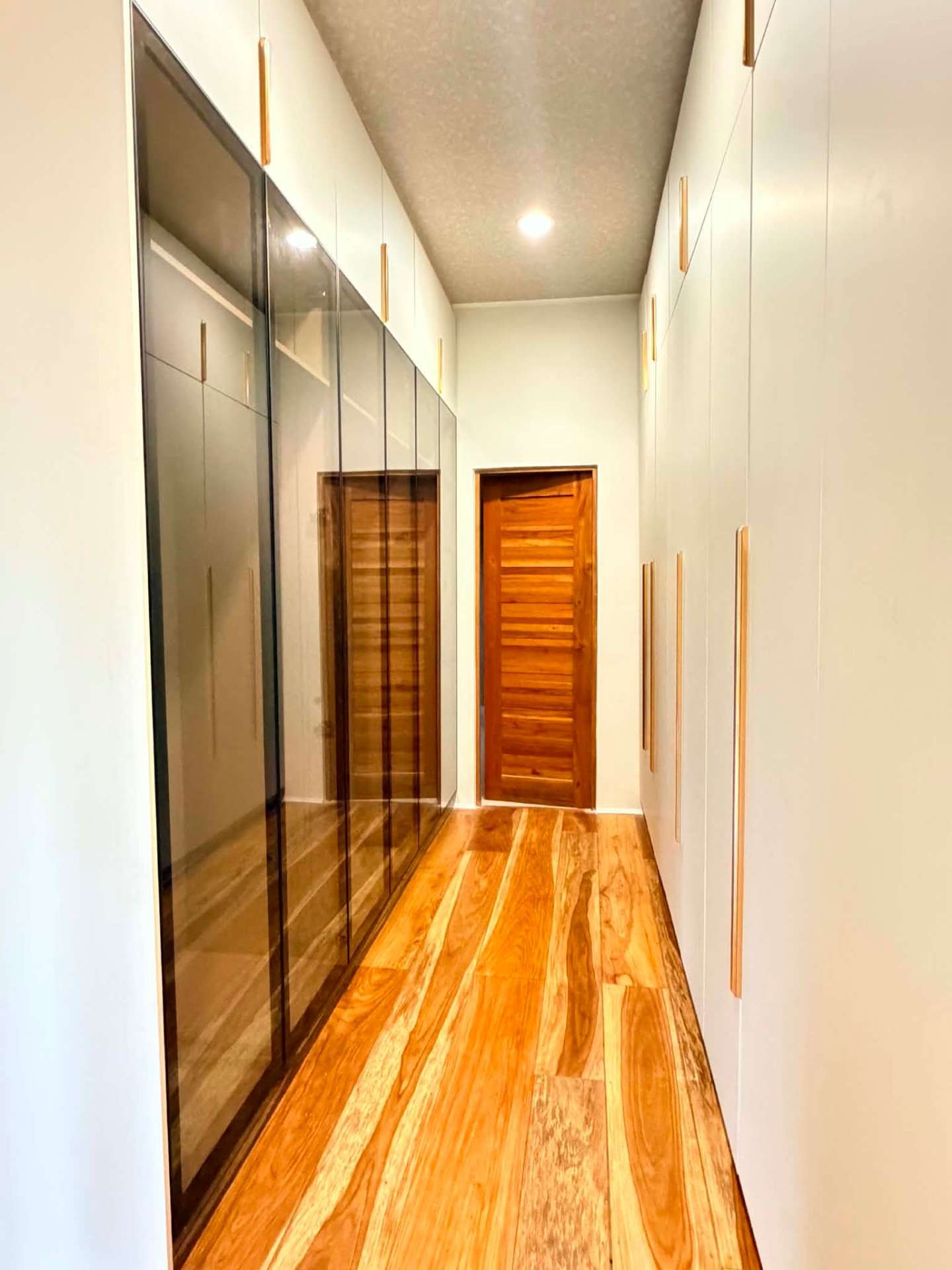 Walk-in closet lined with fitted cabinetry and mirrored doors