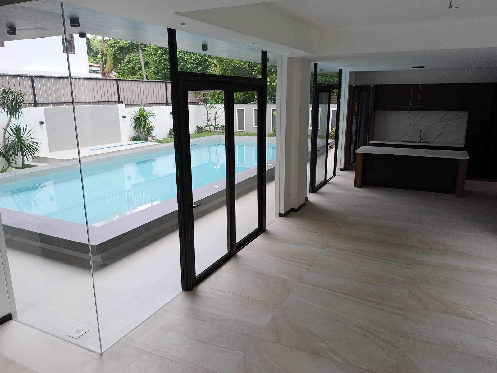 Lanai and open kitchen island looking out to the pool through glass walls