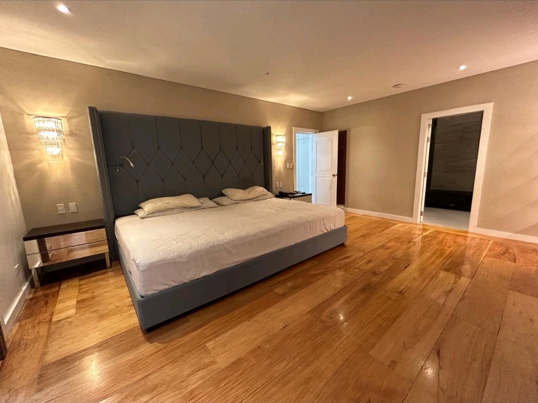 Master suite with upholstered headboard and wide hardwood floors