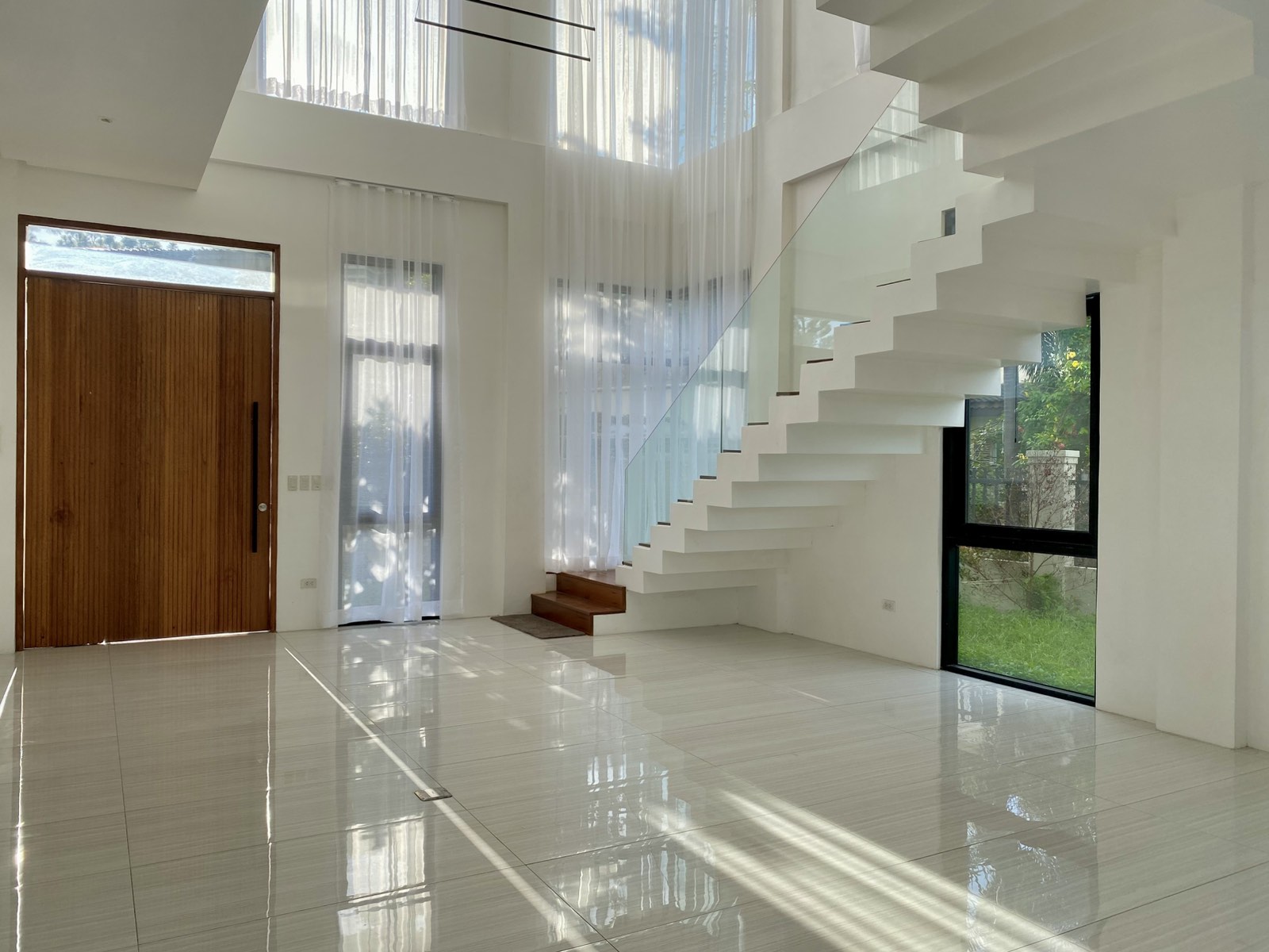 Double-height foyer with mahogany main door and sculptural staircase
