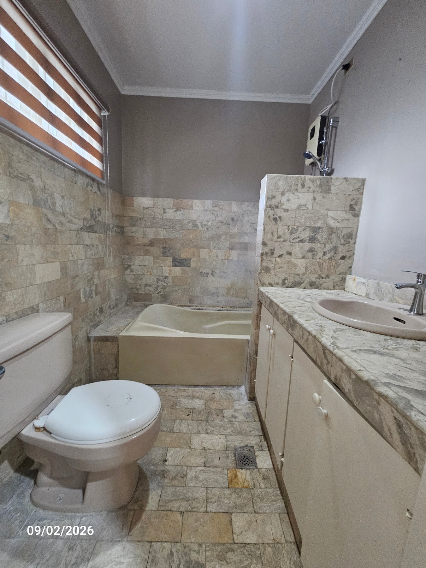 Family bathroom with stone tiling, tub and marble vanity