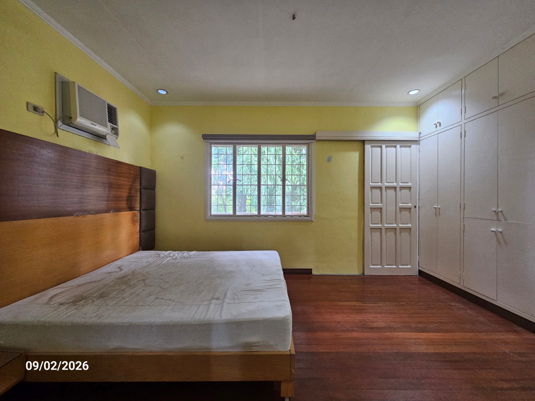 Bedroom with timber headboard and full wall of built-in cabinets