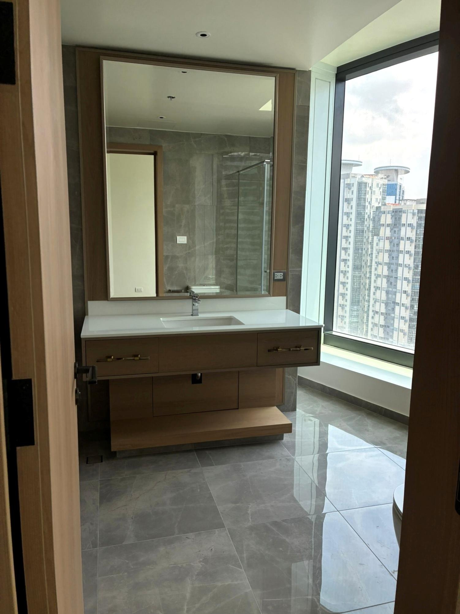 Second bedroom bathroom with wood vanity and city-facing window
