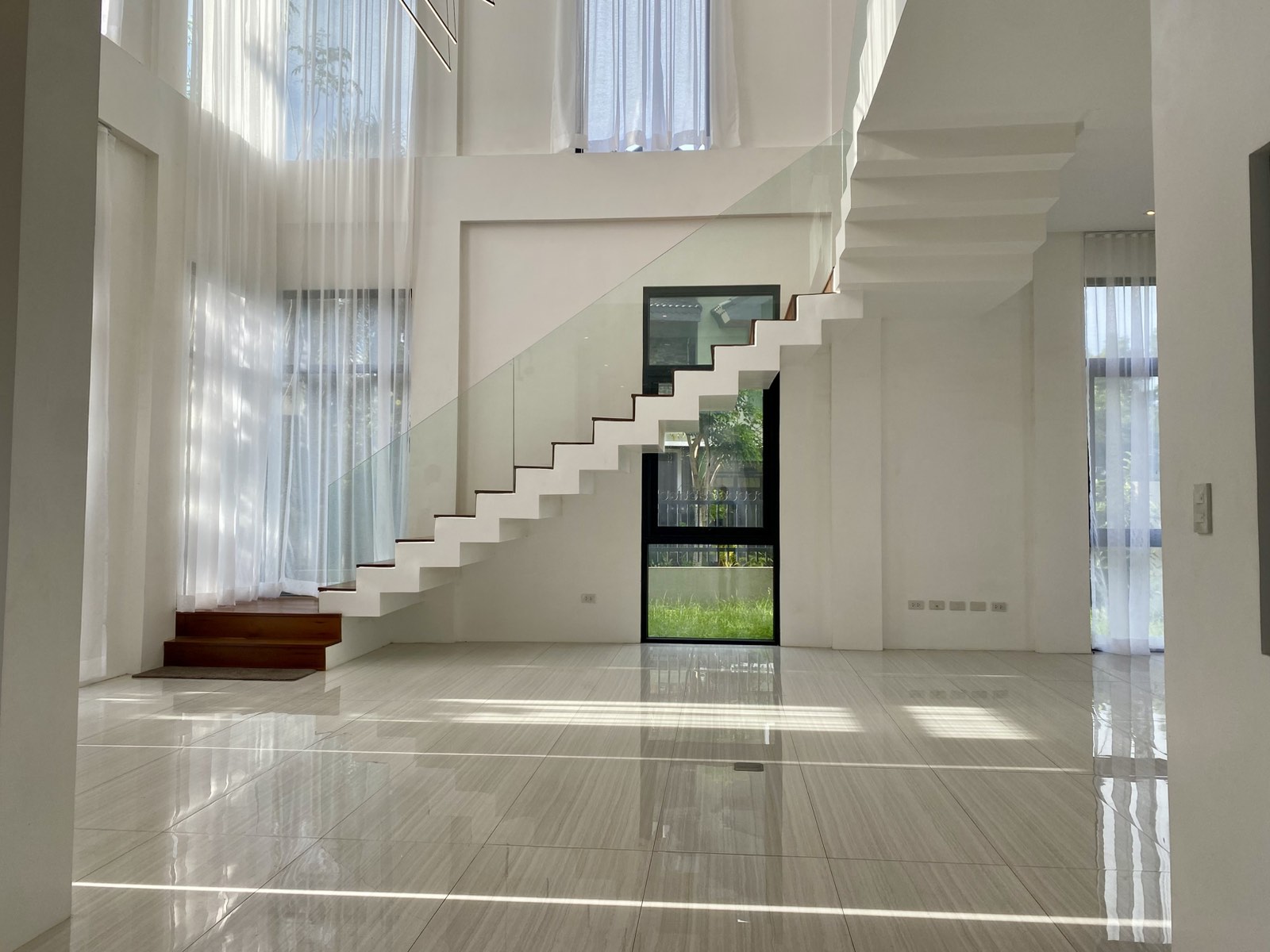 Floating staircase with glass railing under double-height ceilings