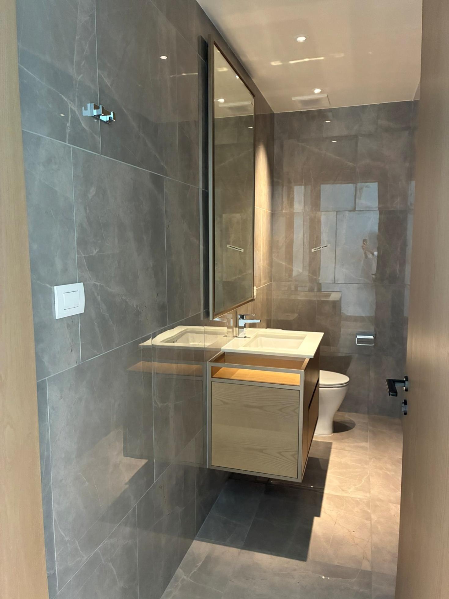 Powder room with floating wood vanity and marble-toned tiles