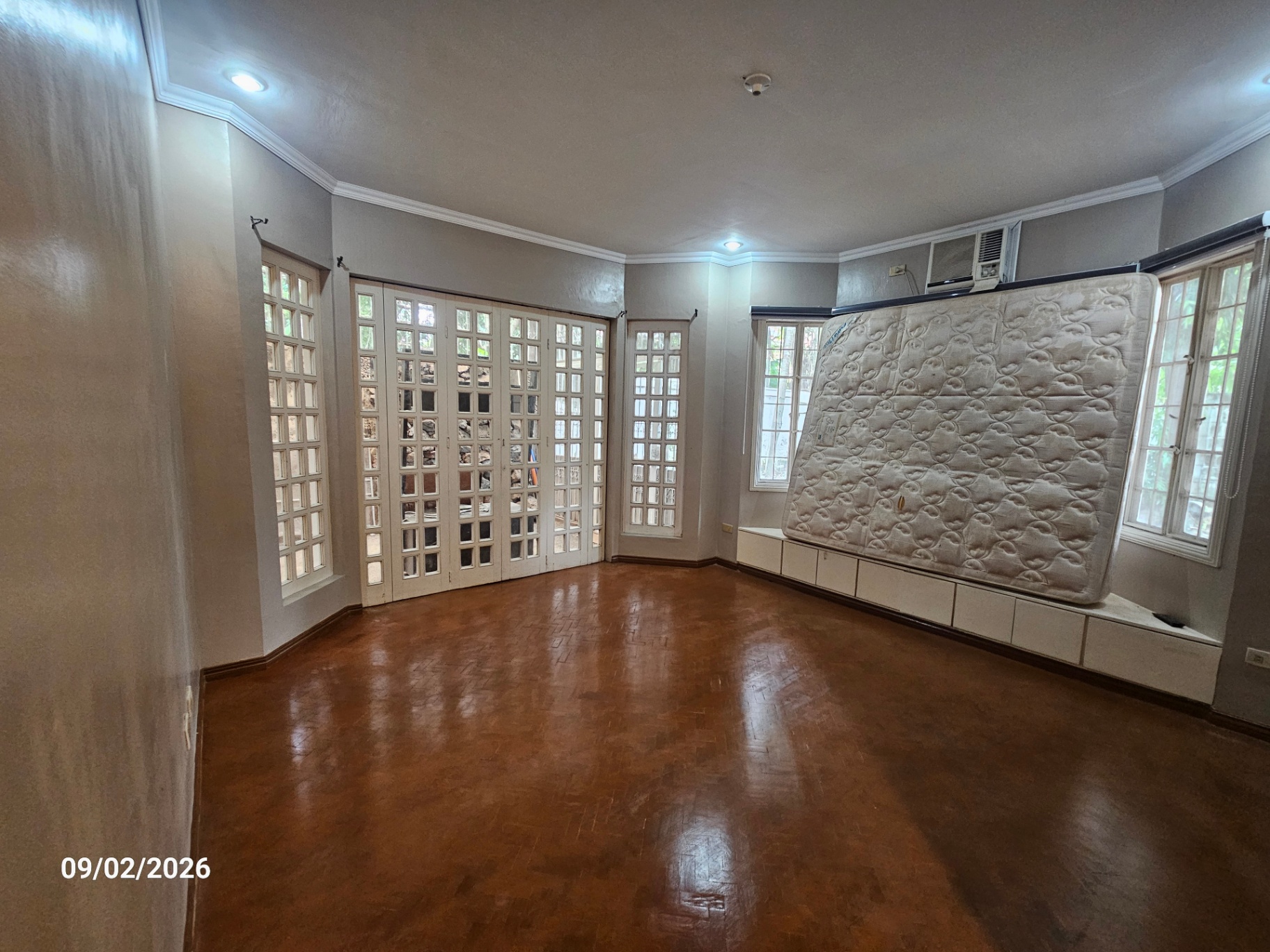 Corner bedroom with parquet flooring and full-height windows