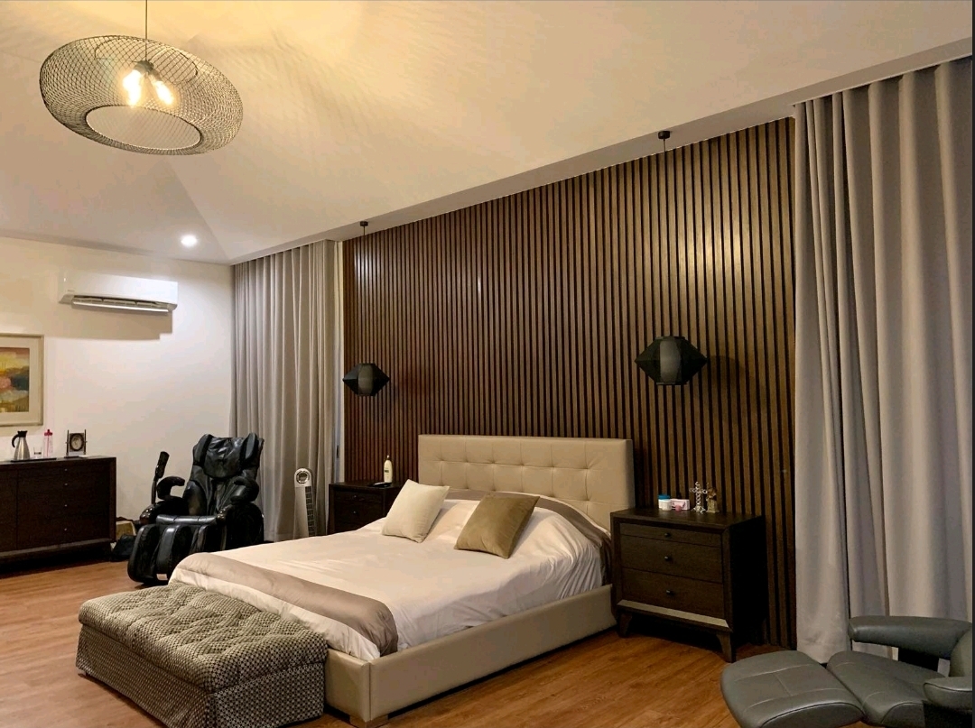Master bedroom with full-height walnut slat feature wall and tufted bed