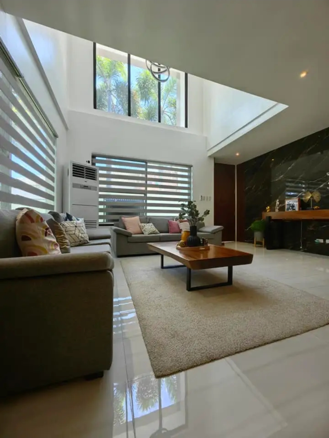 Double-height living area with marble feature wall and floor-to-ceiling windows