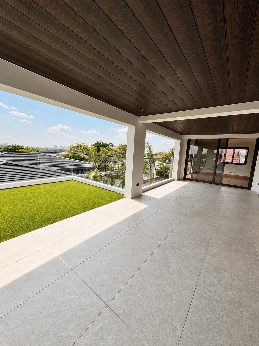 Open deck with lawn and glass railing overlooking the Alabang skyline