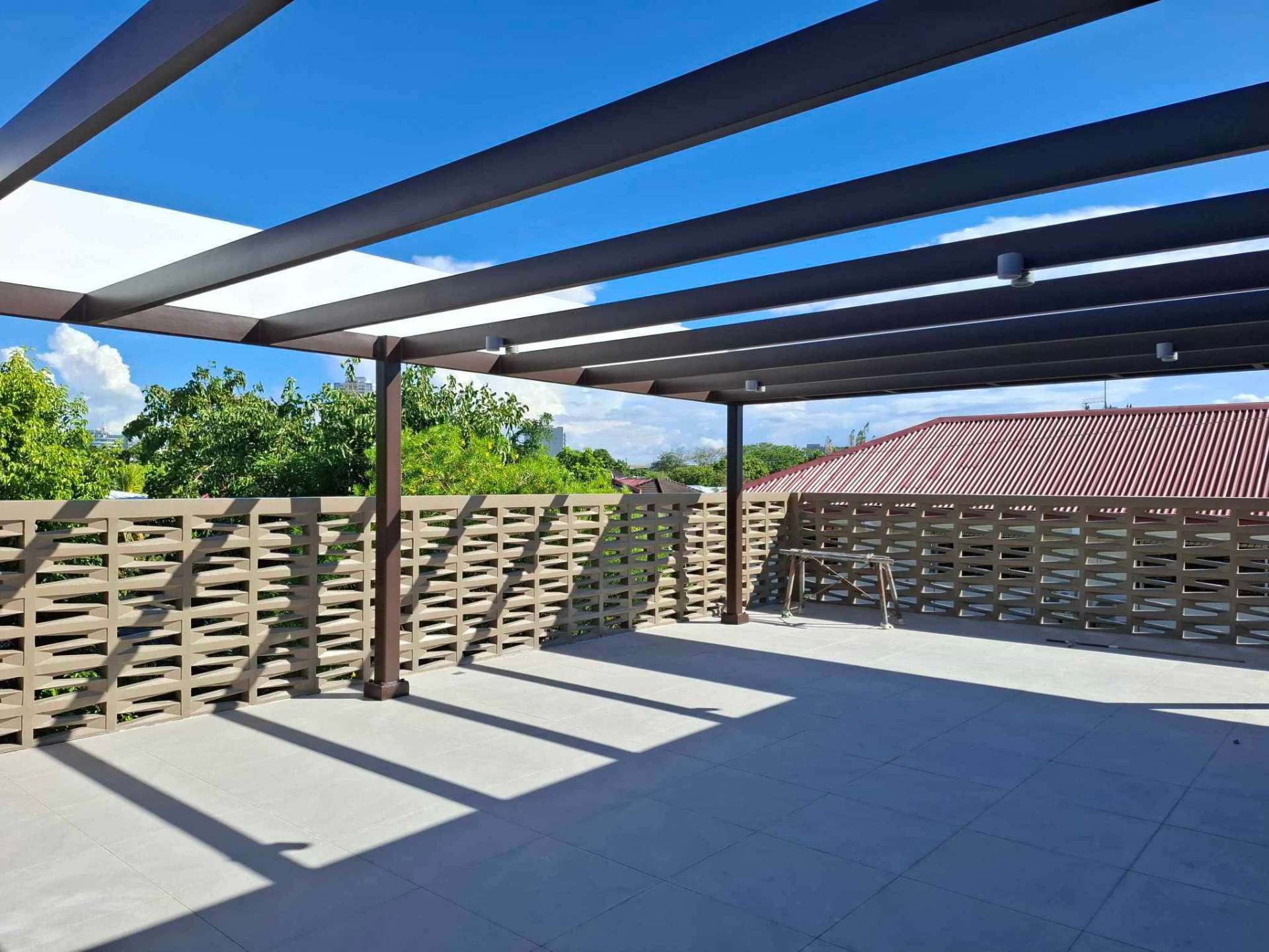 Roof deck with steel pergola and breeze-block parapet overlooking the village