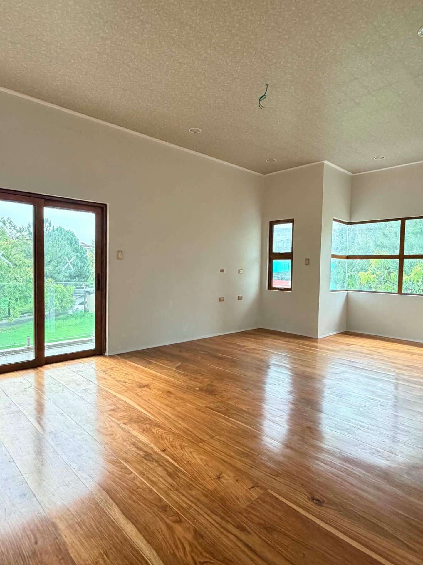 Bedroom in narra flooring with corner windows and balcony access