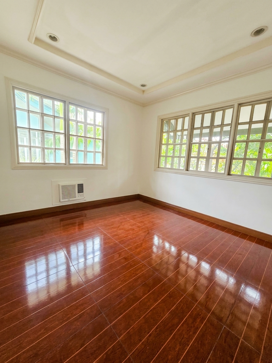 Bright bedroom with polished hardwood floors and garden-view windows