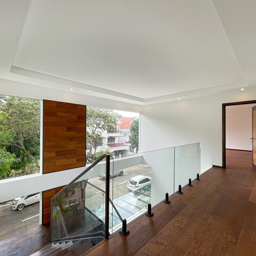 High-ceiling landing with floating stairs, glass railing, and wood feature panel