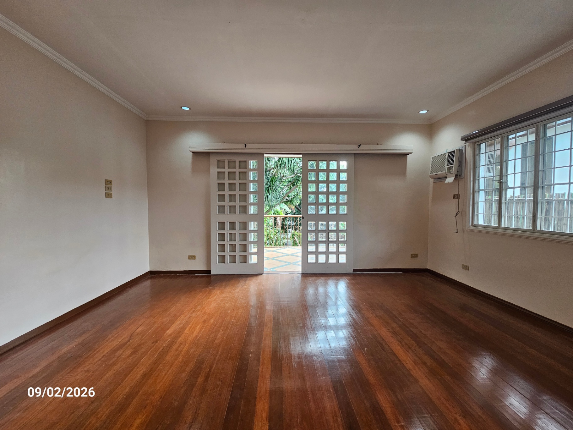 Upper bedroom with hardwood floors opening to a garden balcony