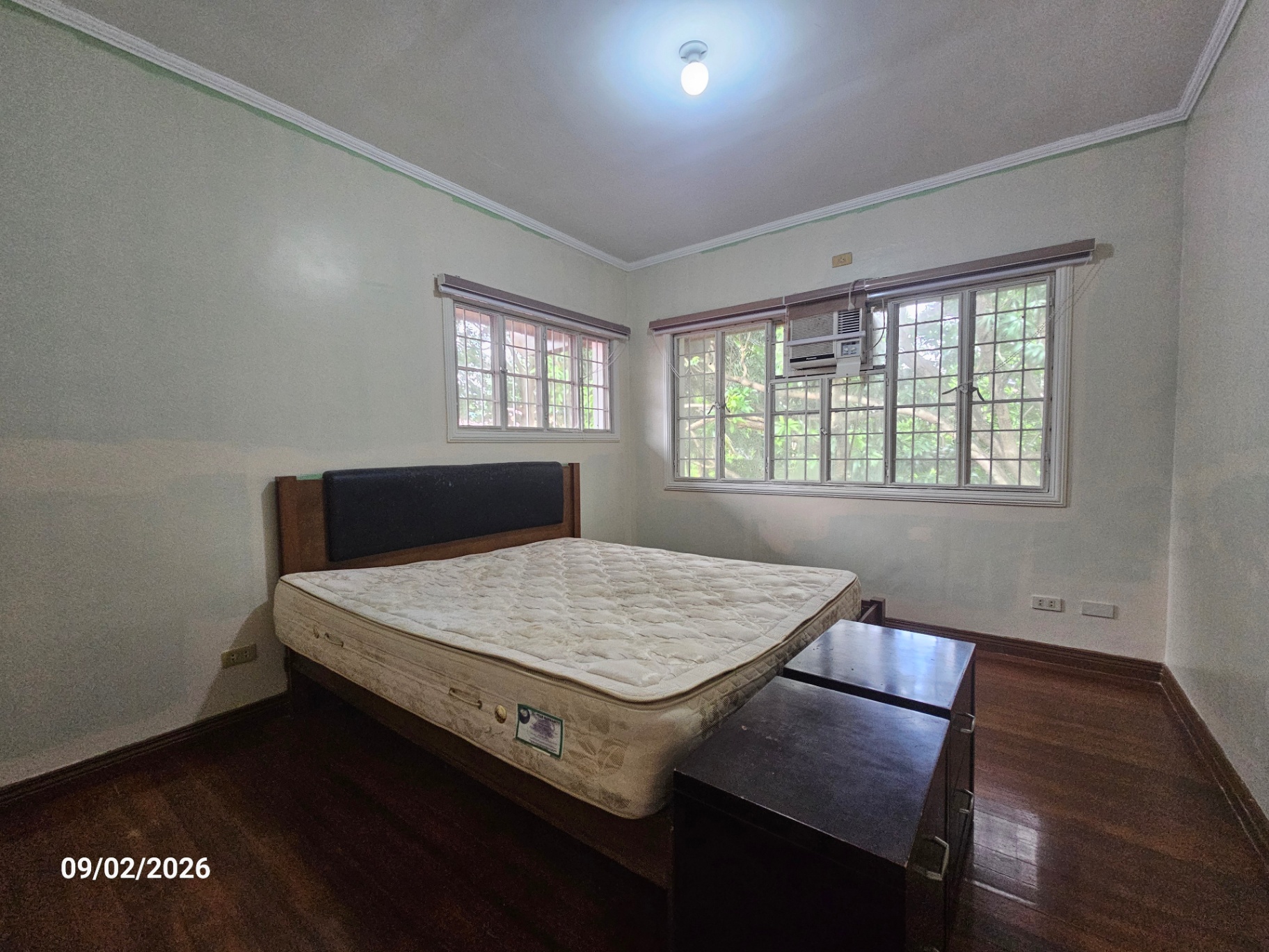 Bedroom with built-in headboard and garden-view windows