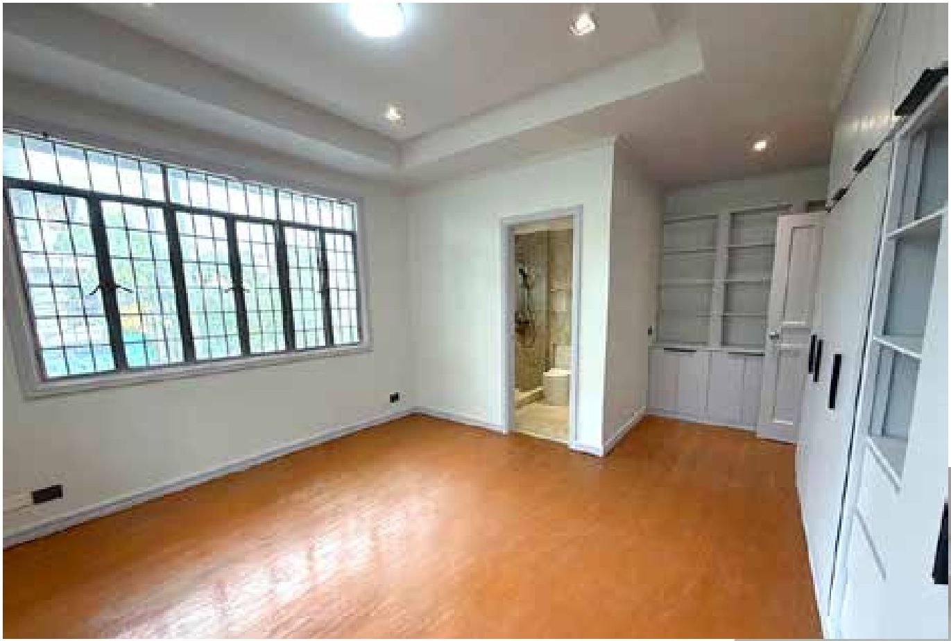 Bedroom with hardwood flooring, built-in cabinetry and en-suite bath