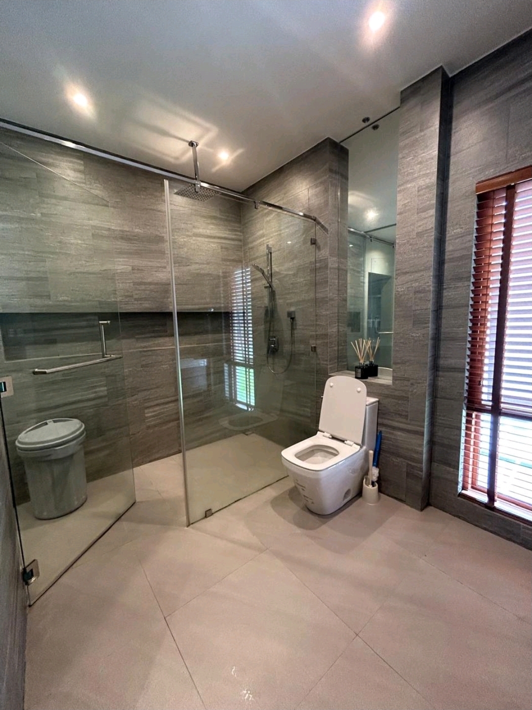 Bathroom with stone-clad walk-in shower and glass enclosure