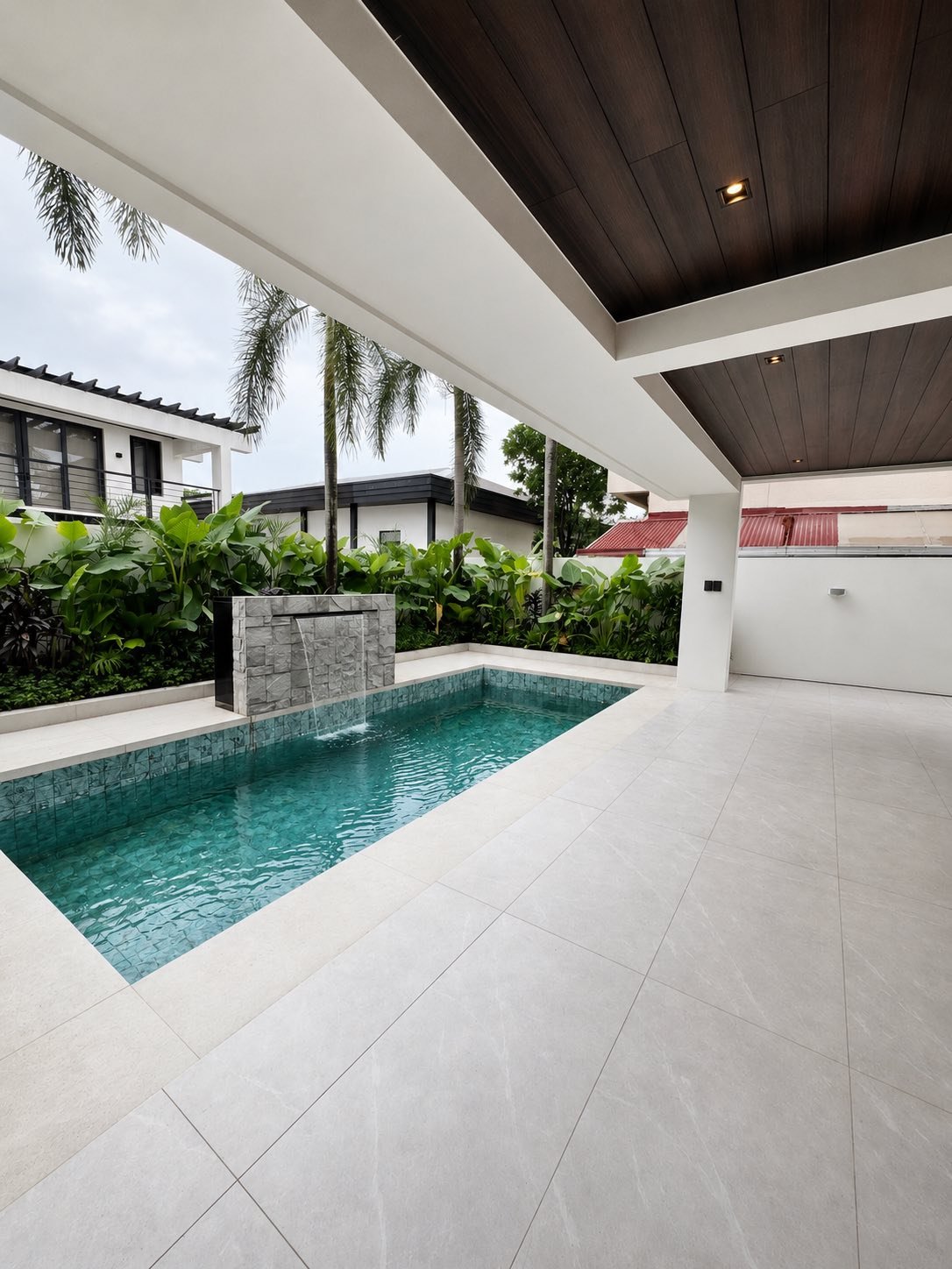 Swimming pool with stone water feature under a timber-lined lanai