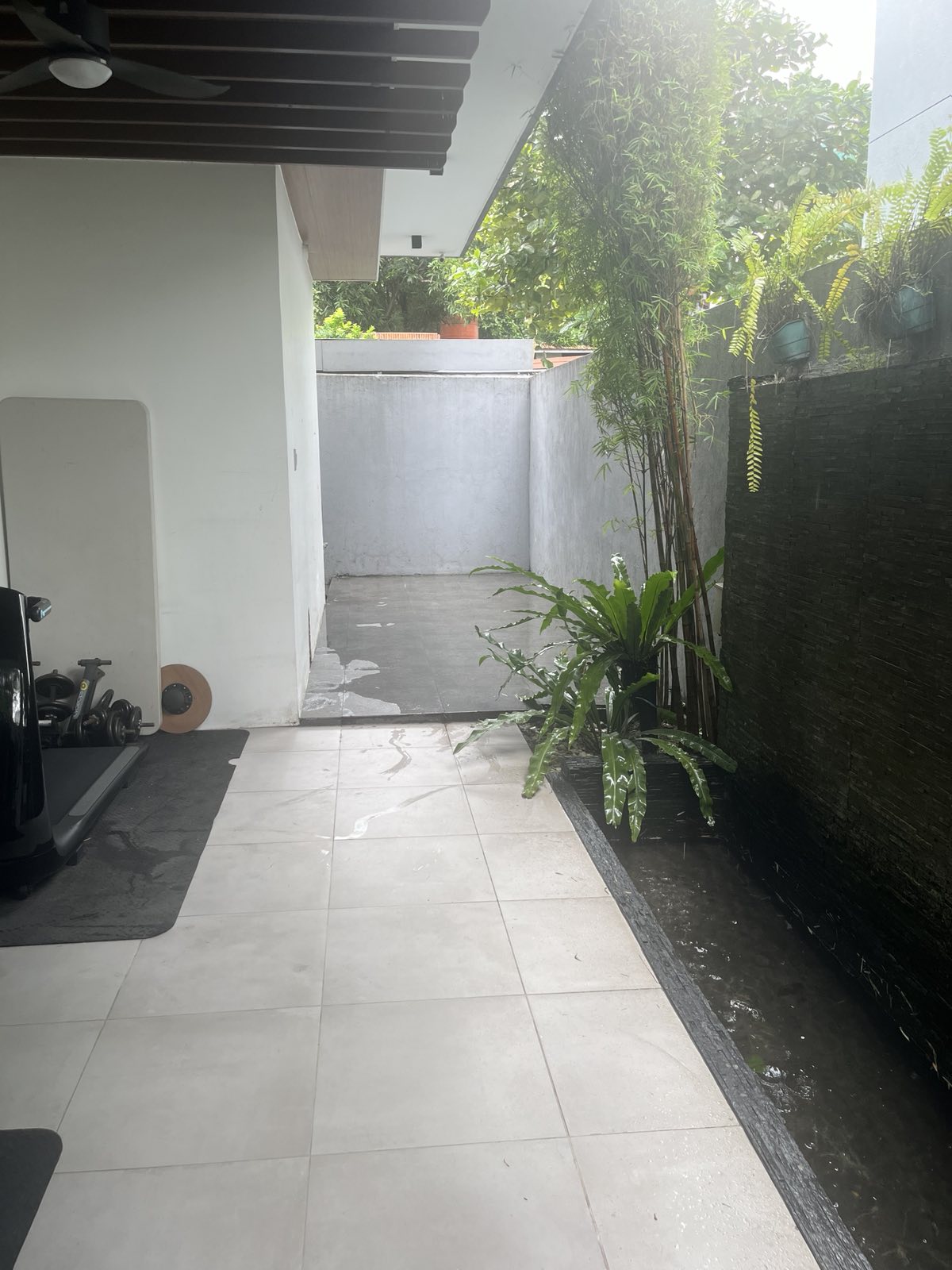 Side lanai and gym extension with tiled deck, water feature and tropical planting