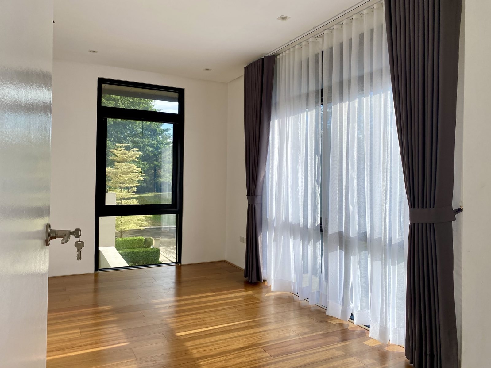 Bedroom with garden-view window and warm wood flooring