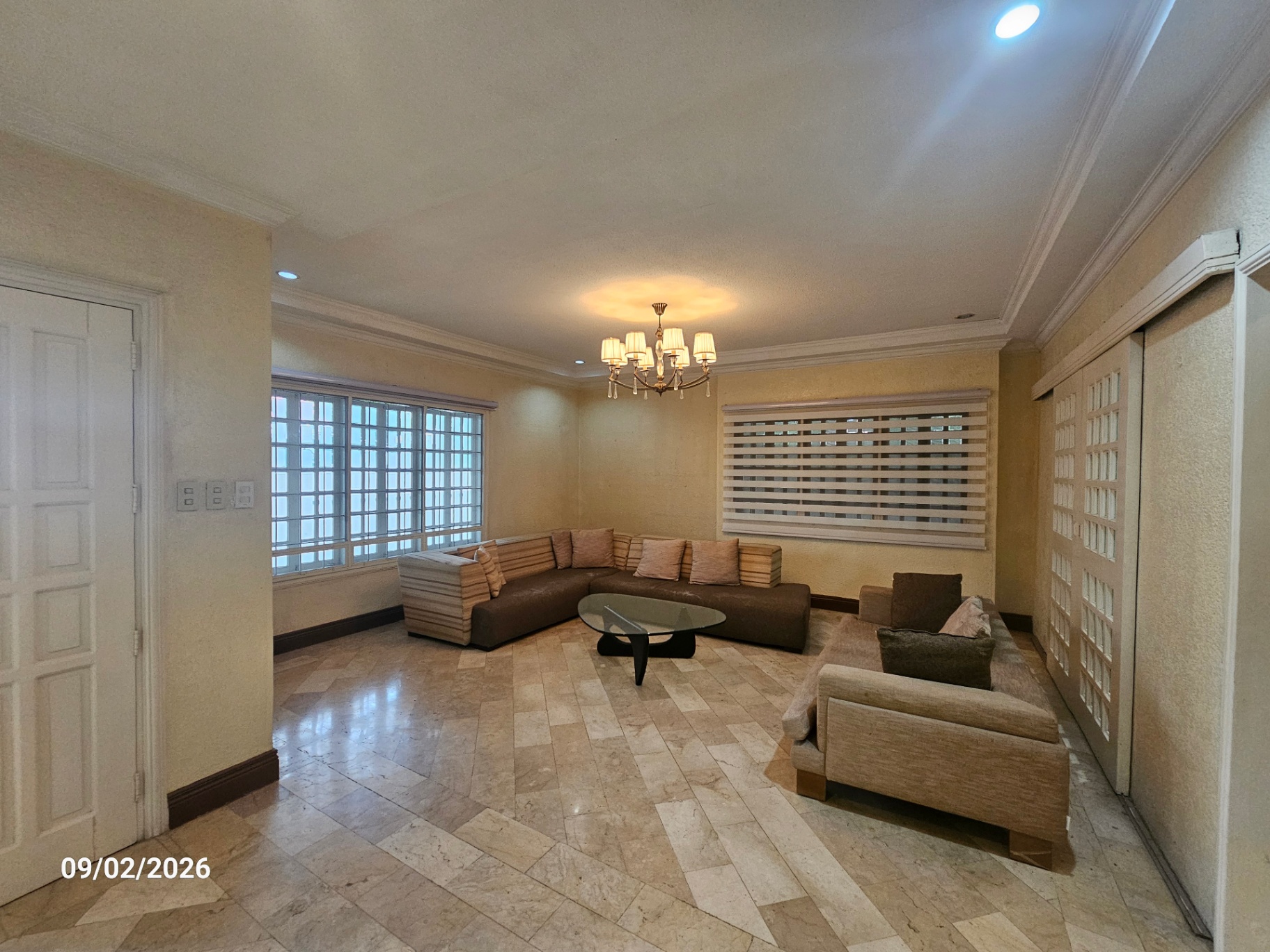 Formal living room with marble flooring, chandelier and sectional seating
