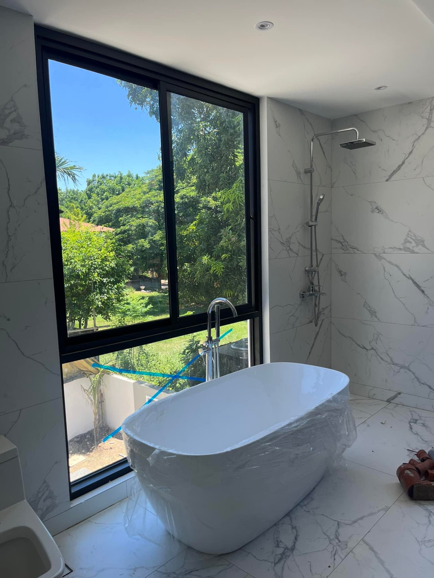 Ensuite bathroom with freestanding soaking tub beside a full-height garden window