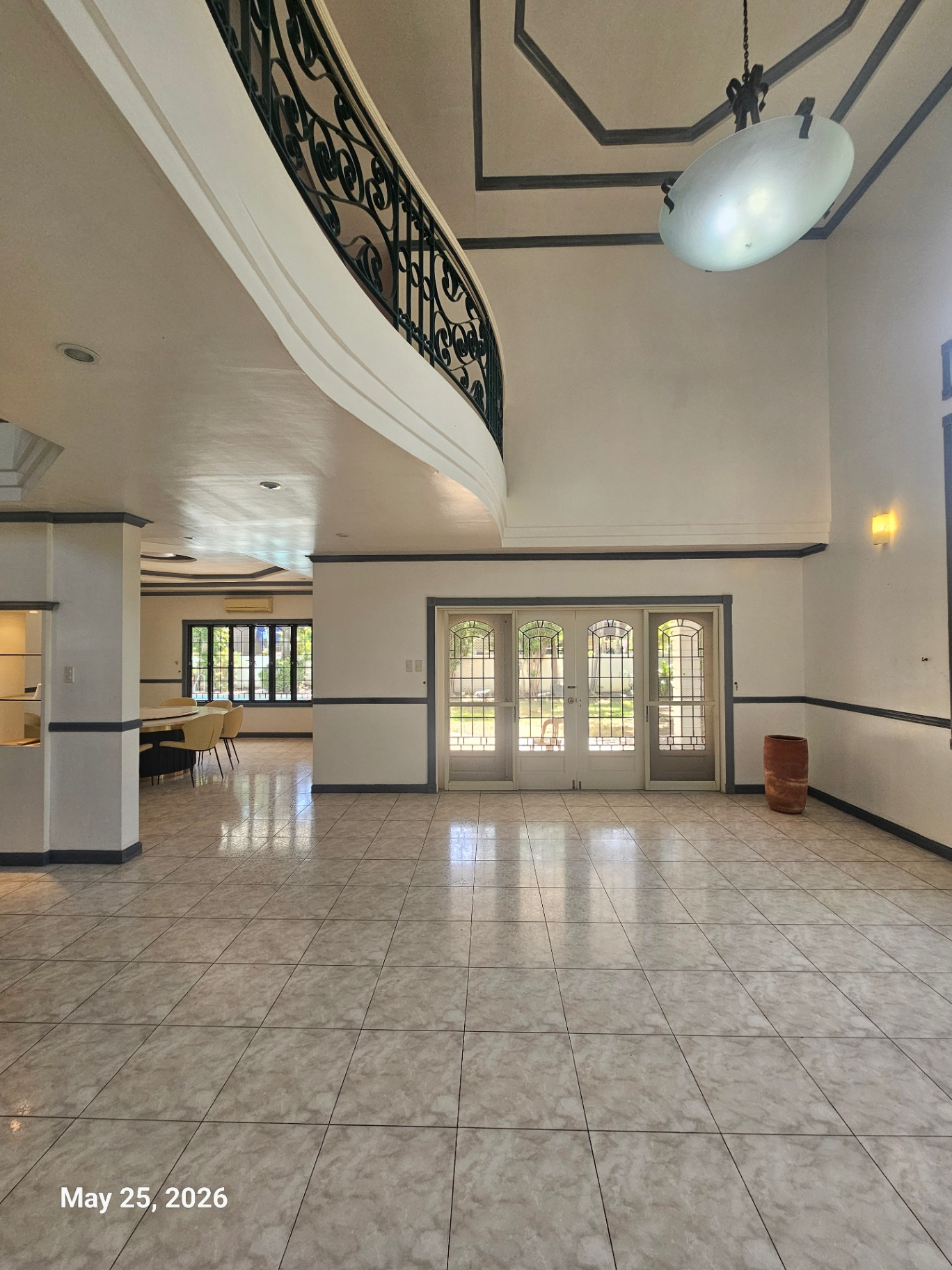 High-ceiling living room with curved staircase and garden doors