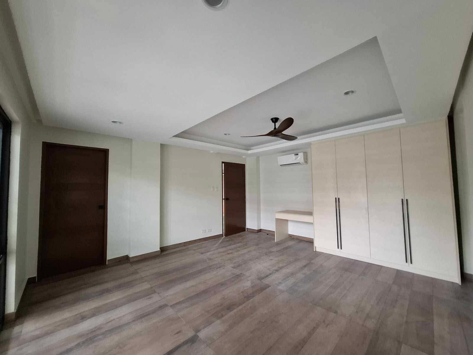 Master bedroom with built-in wardrobe, vanity, and wood-look flooring