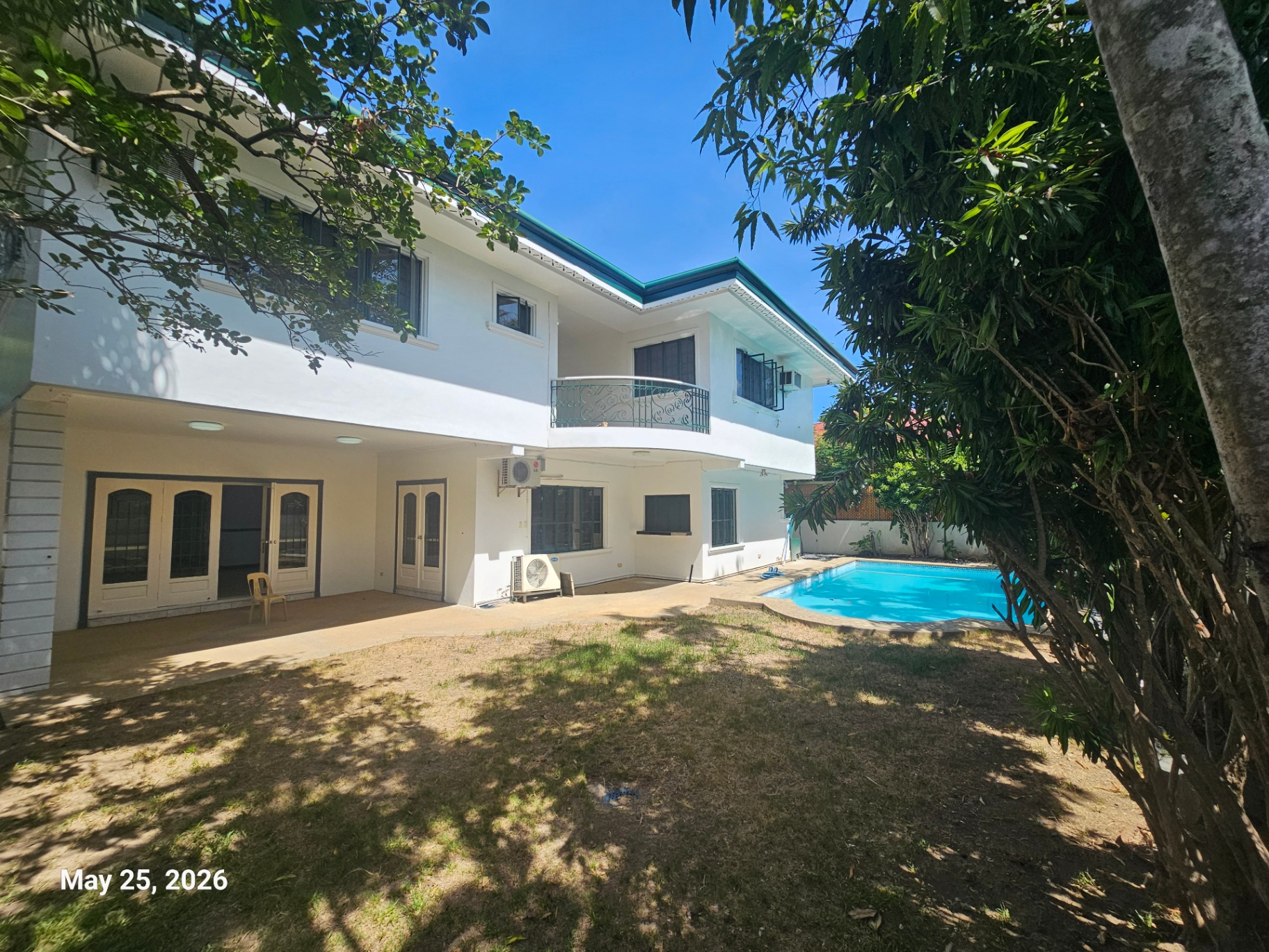 Swimming pool and garden lawn framed by mature trees