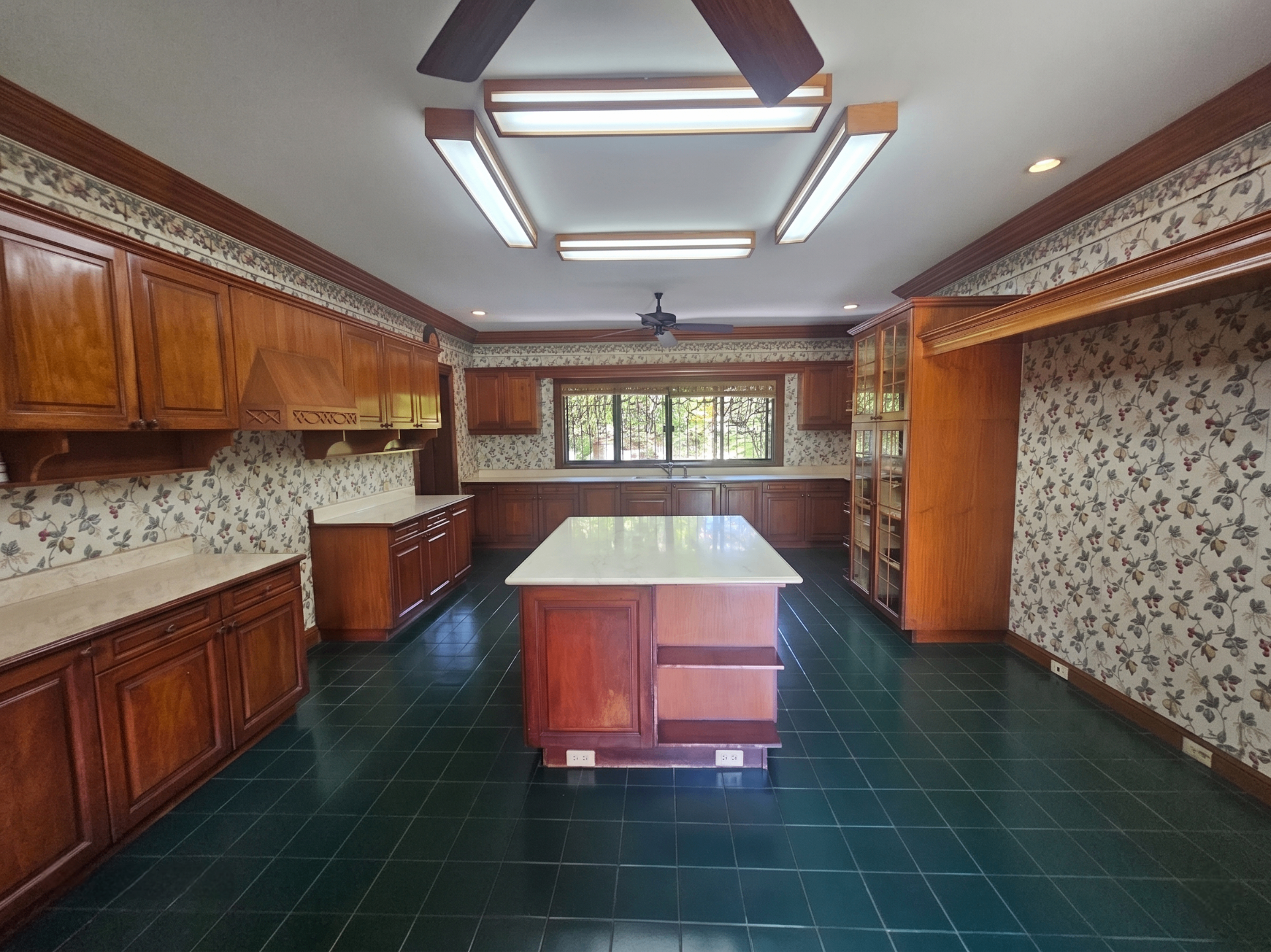 Wide view of the main kitchen with island, extensive cabinetry, and patterned wall finish